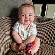 Kobie is registered to the contest to win money with this photo: baby, child, smile, toy, armchair, corduroy, indoors, cute, happy, person, infant, skin, clothing, feet, furniture, face, hands, seated, door, home