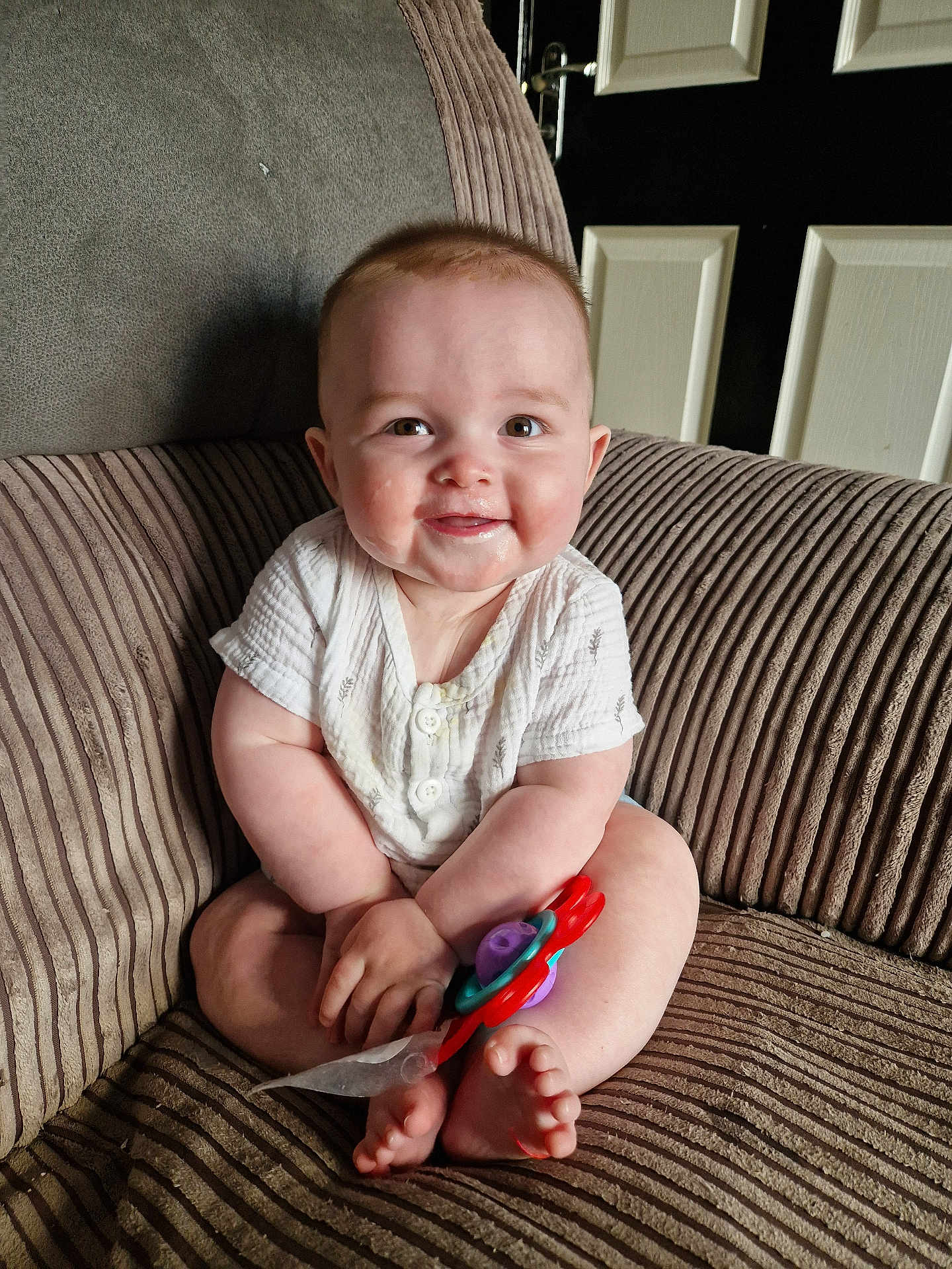 Kobie is registered to the contest to win money with this photo: baby, child, smile, toy, armchair, corduroy, indoors, cute, happy, person, infant, skin, clothing, feet, furniture, face, hands, seated, door, home