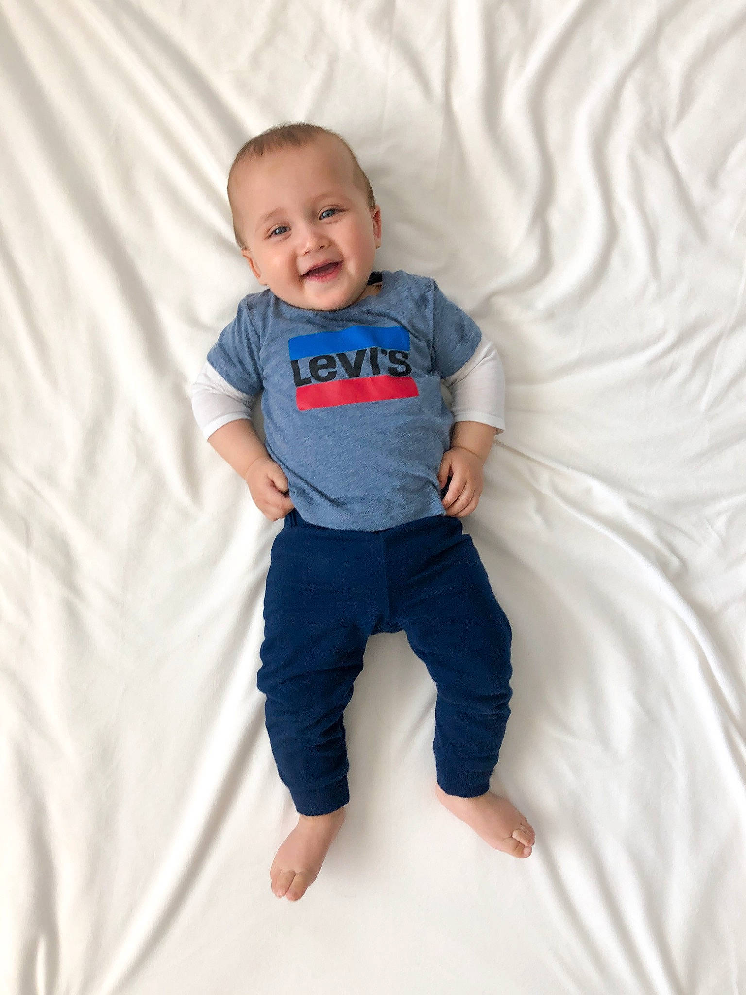 Cole is registered to the contest to win money with this photo: arm, baby_toddler_clothing, comfort, elbow, face, gesture, hand, happy, head, human_body, joy, knee, leg, neck, person, sleeve, smile, sportswear, stomach, t_shirt