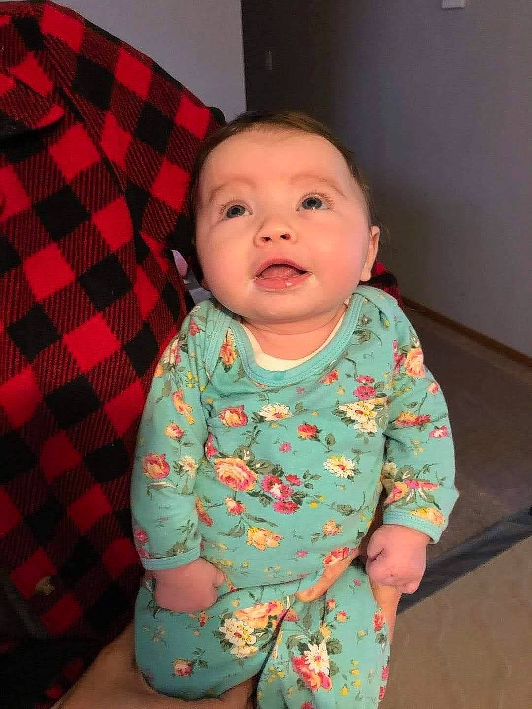 June is registered to the contest to win money with this photo: baby, baby_toddler_clothing, cheek, chin, collar, comfort, eye, face, head, iris, linens, nose, pattern, person, pink, plaid, skin, sleeve, tartan, tints_and_shades