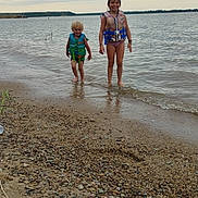 Ella Mae Lynn joined the competition — help win amazing prizes! child, children, life_jacket, water, lake, shore, pebbles, sand, cloudy_sky, outdoor, smiling, wet_hair, summer, play, nature, water_sports, fun, safety, person, recreation