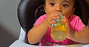 Camryn is registered to the contest to win money with this photo: baby, bottle, child, curiosity, curly_hair, cute, drinking, expression, face, feeding, hair_buns, high_chair, home, indoor, person, pink_shirt, seated, table, toddler, young_child