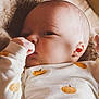 baby, infant, blanket, onesie, pumpkin_pattern, cute, face, hand, thumb_sucking, soft_texture, fur, cozy, sleepwear, closeup, portrait, child, newborn, resting, indoors, comfort
