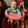 adult, carpet, child, cute, furniture, hair_up, hands, happy, home, indoor, legs, person, pink_crocs, pink_walker, playful, red_dress, toddler, tongue_out, walker, wood_floor