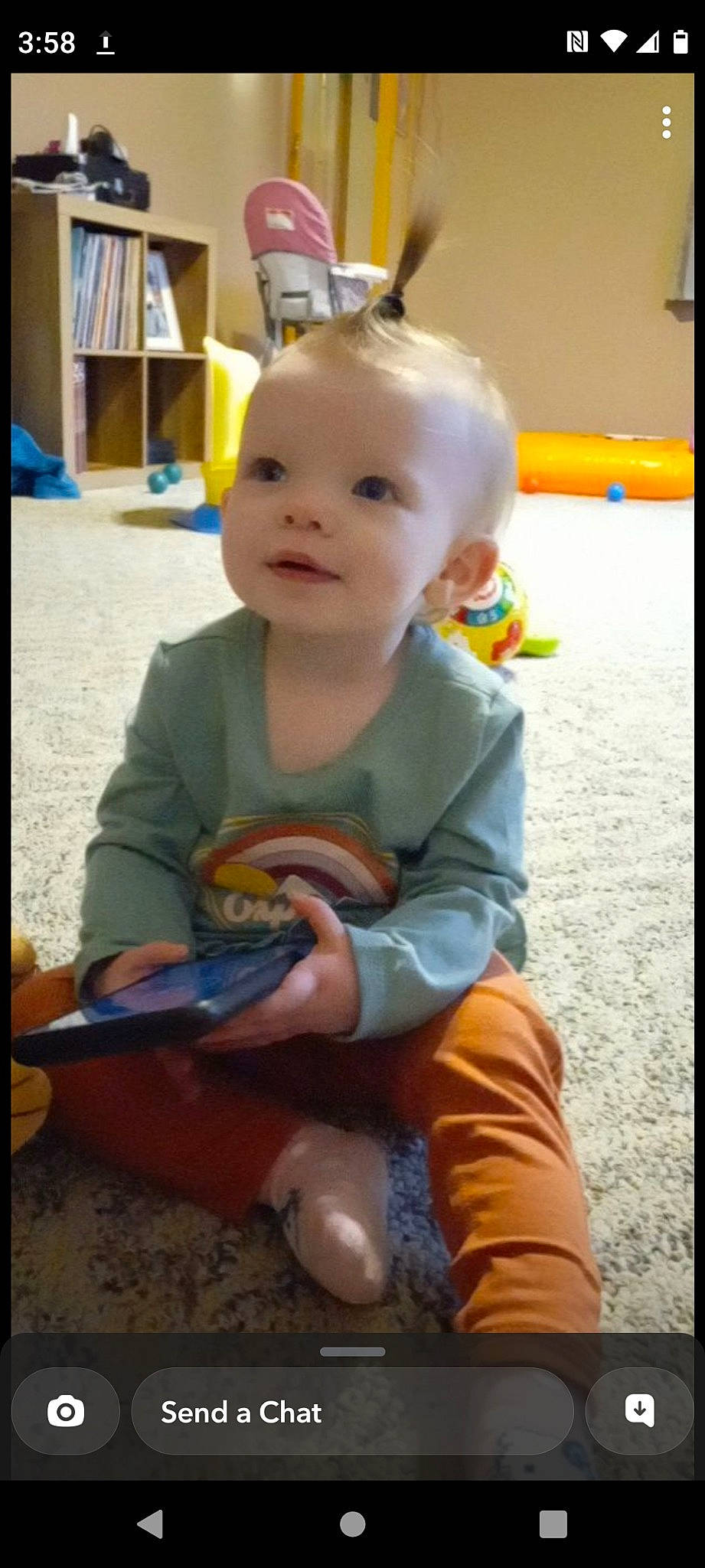 Ashlyn joined the competition — help win amazing prizes! baby, baby_playing_with_toys, baby_toddler_clothing, baby_toys, biting, bookcase, chair, child, flooring, fun, play, room, shelf, sitting, smile, t_shirt, thumb, toddler, vacation