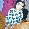 Josephine is registered to the contest to win money with this photo: toddler, child, indoor, heart_pattern, beanie, black_hat, pink_sneakers, wooden_floor, playhouse, toy_house, backpack, casual_clothing, long_hair, white_sweatshirt, pants, footwear, holding_spoon, young_child, person, floor