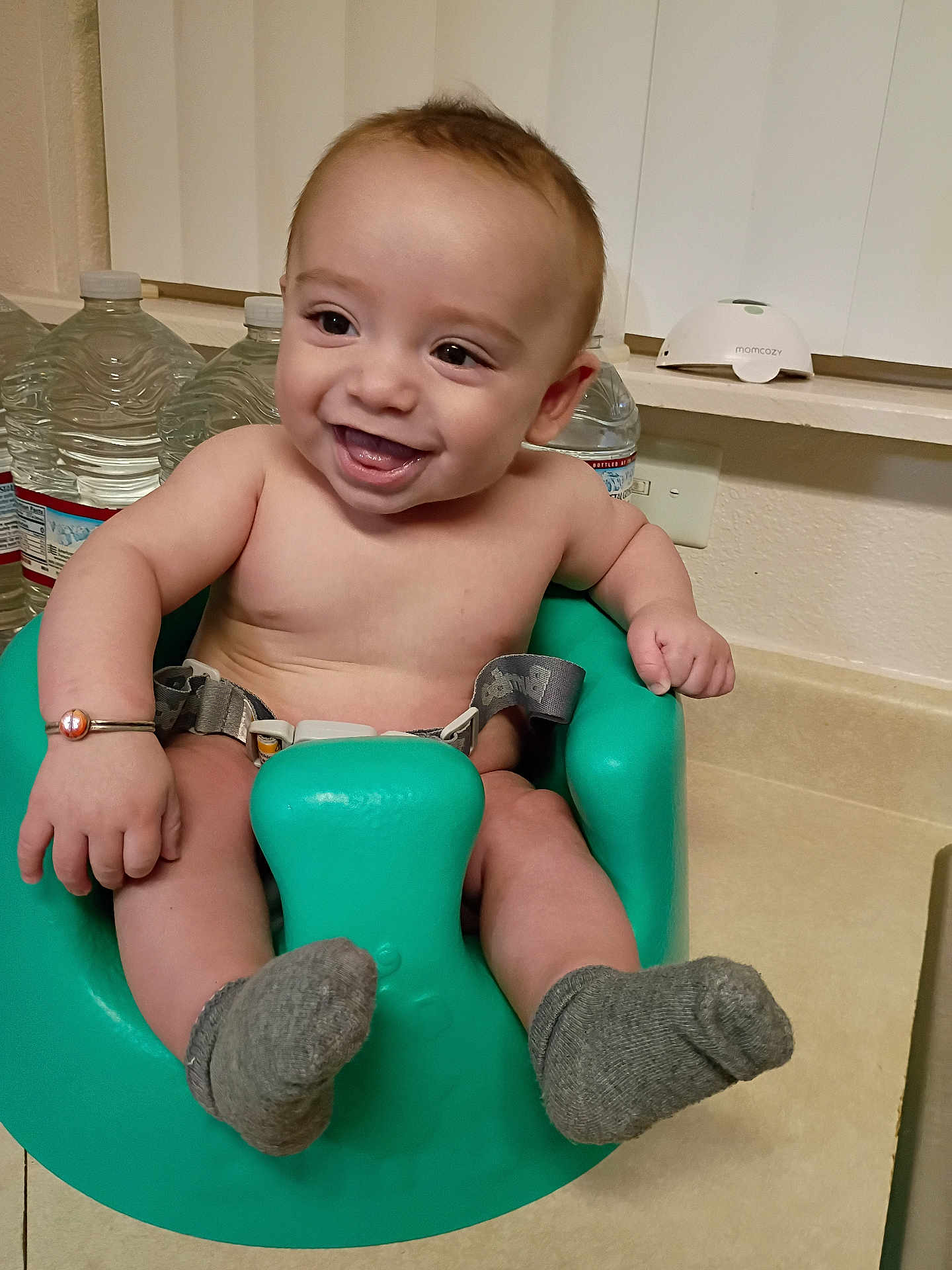 Isaiyel Gurule is registered to the contest to win money with this photo: baby, smiling, baby_seat, socks, bracelet, indoor, water_bottles, countertop, happy, child, person, infant, skin, arm, leg, face, mouth_open, eyes, hair, home