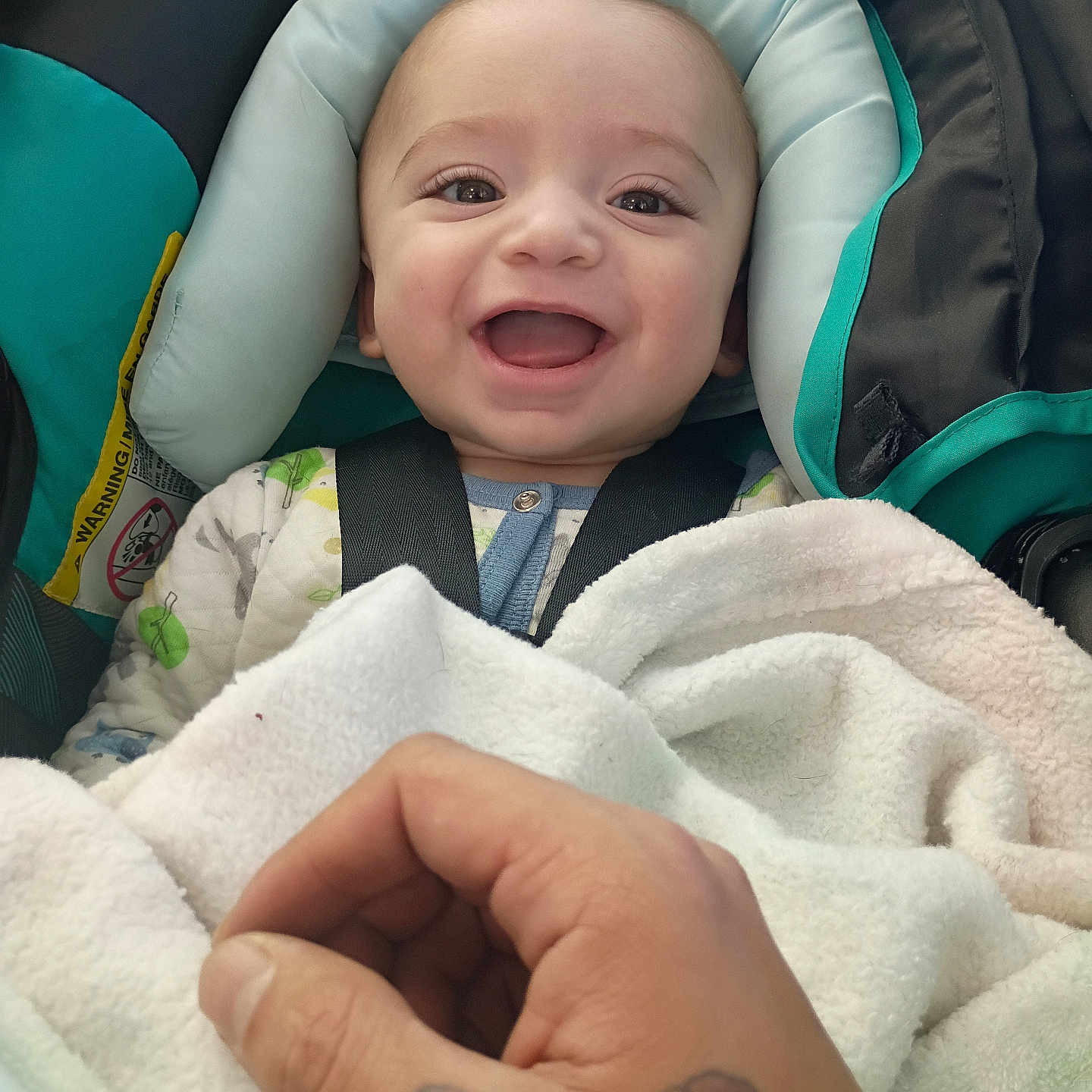 Isaiyel Gurule joined the competition — help win amazing prizes! baby, baby_clothes, blanket, car_seat, child, closeup, clothing, comfort, cute, face, hand, happy, indoor, infant, person, portrait, seatbelt, smiling, tattoo, young_child