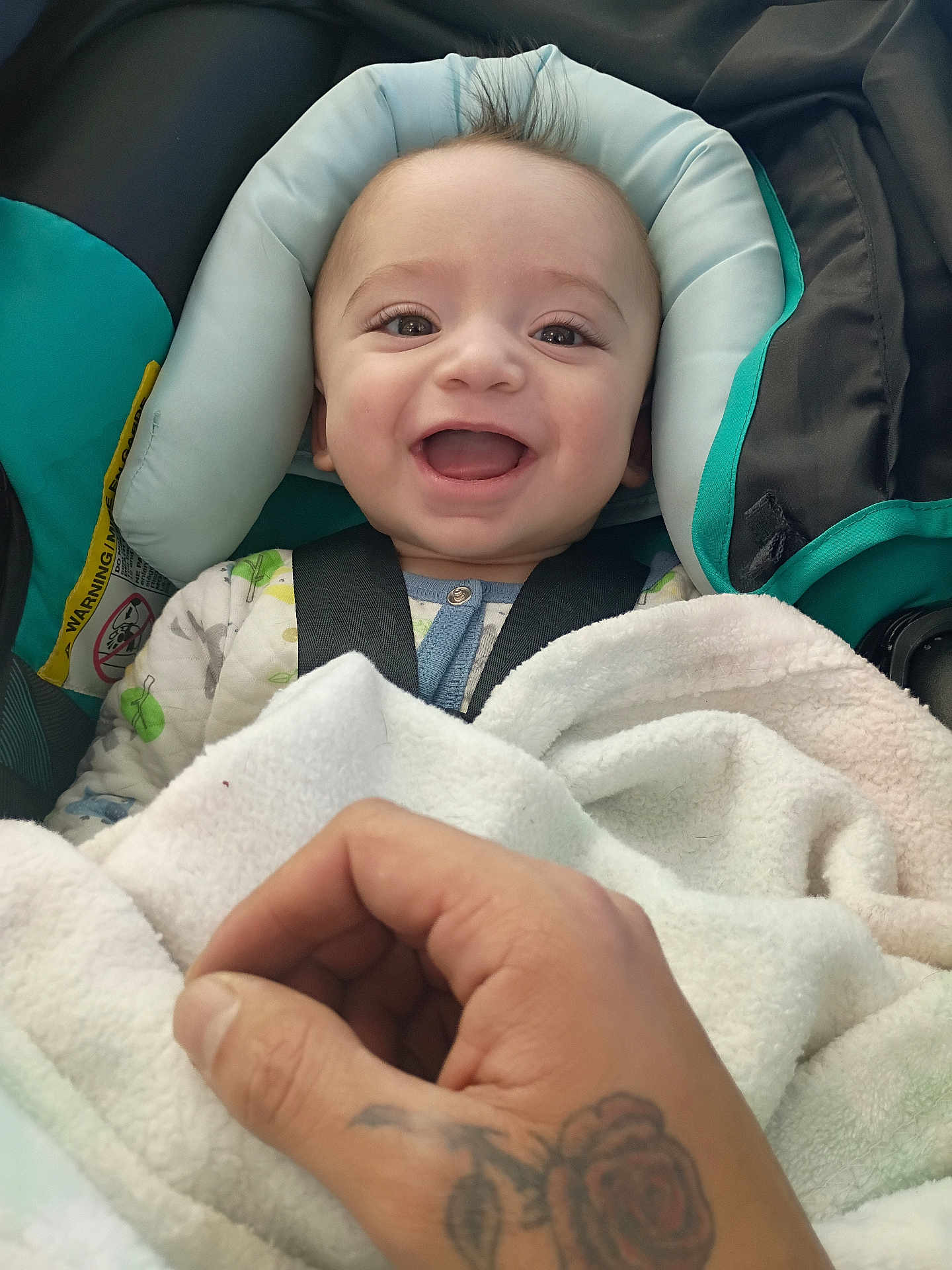 Isaiyel Gurule joined the competition — help win amazing prizes! baby, smiling, car_seat, blanket, hand, tattoo, child, infant, clothing, person, happy, face, portrait, indoor, cute, young_child, seatbelt, closeup, baby_clothes, comfort