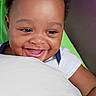baby, child, smiling, happy, portrait, face, head, curly_hair, eyes, mouth, teeth, sitting, indoor, cushion, shirt, white_clothing, close_up, joyful, infant, person