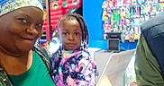 Kalise is registered to the contest to win money with this photo: child, adult, family, selfie, portrait, indoor, store, shop, retail, shelves, colorful, braids, headscarf, jacket, clothing, smiling, camera, customer, counter, photograph