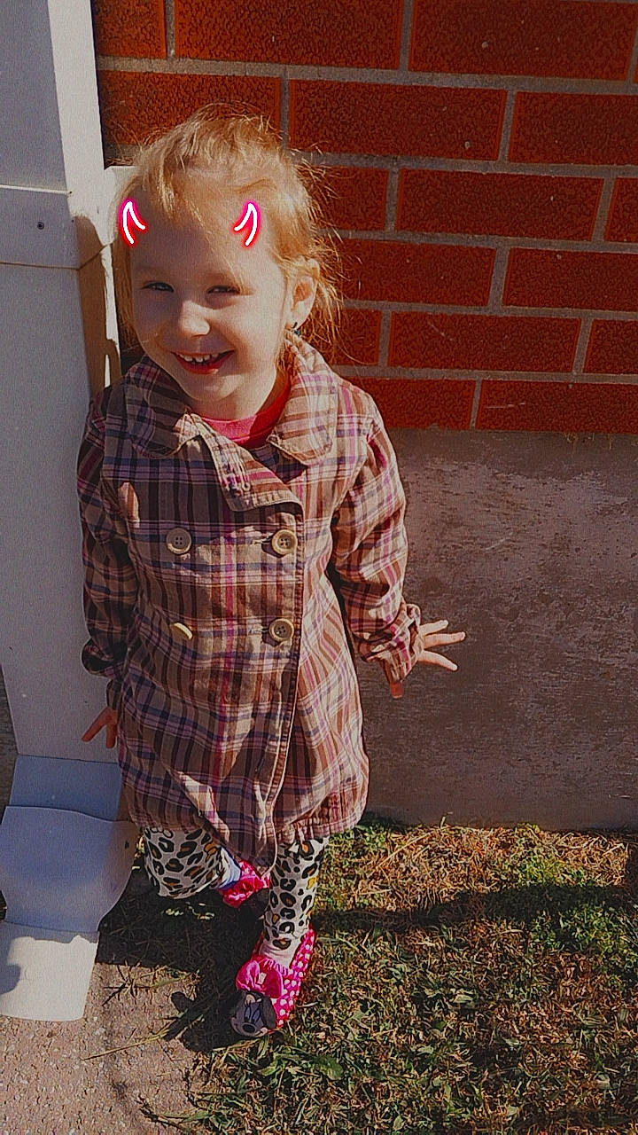 Brittany is registered to the contest to win money with this photo: baby_toddler_clothing, blond, brick, brickwork, child, flooring, fun, grass, hair, hairstyle, happy, joy, pattern, person, plaid, sitting, sleeve, standing, tartan, tints_and_shades