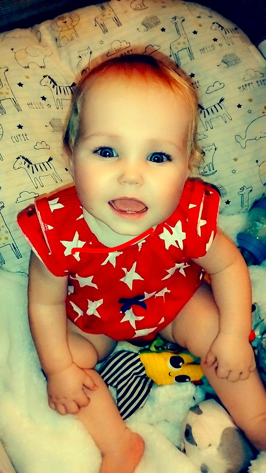 Kahleesi Lynn is registered to the contest to win money with this photo: baby, child, smiling, red_clothing, stars_pattern, blue_eyes, toy, blanket, pillow, animal_prints, cute, happy, indoors, sitting, infant, soft_texture, playful, face, person, closeup