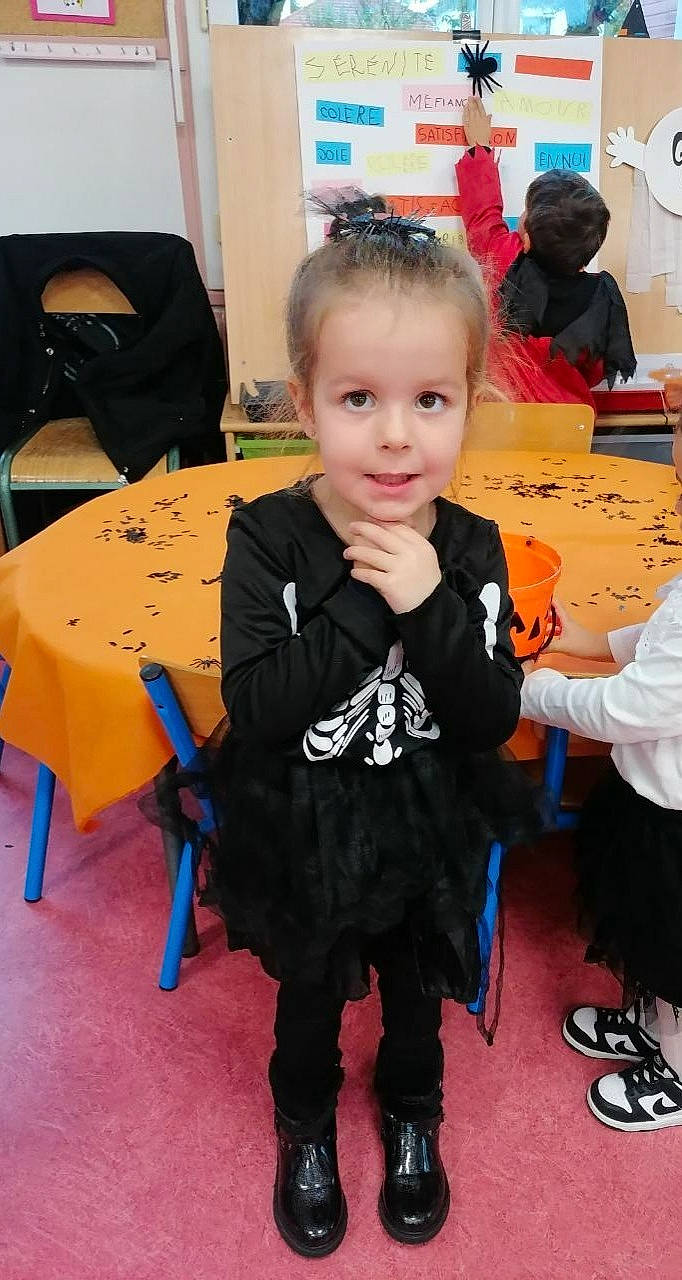 Hanaé a rejoint le concours — aidez-le/la à gagner de superbes lots ! black, chair, child, costume, desk, event, face, flooring, fun, party, person, room, sandal, sitting, smile, t_shirt, table, toddler, under_exposed