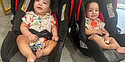 Asiel And Adriel joined the competition — help win amazing prizes! baby, toddler, car_seat, child, indoor, floor, clothing, patterned_shirt, footwearless, smiling, sitting, person, cute, matching_outfits, infant, seat_belt, car_seat_strap, carpet, wood_flooring, happy