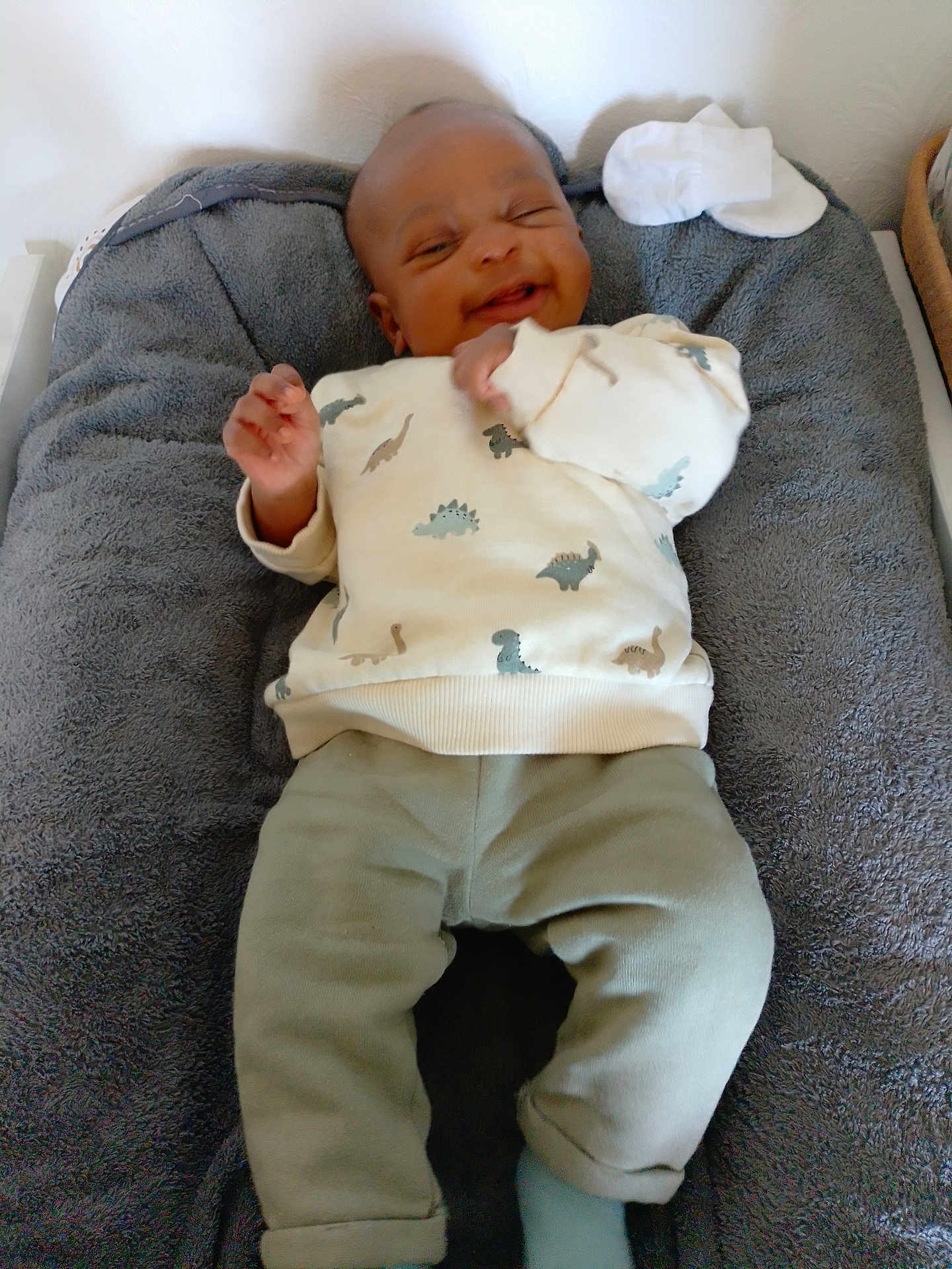 Hamza participe au concours pour gagner de l'argent avec cette photo : baby, infant, smiling, dinosaur_print, sweater, pants, socks, blanket, lying_down, happy, indoors, soft_texture, child, cute, cozy, person, young, apparel, resting, portrait