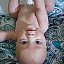 baby, infant, child, upside_down, blue_eyes, bare_chest, arms_raised, blanket, patterned_blanket, cute, playful, skin, face, head, lying_down, indoors, closeup, adorable, expression, young_child