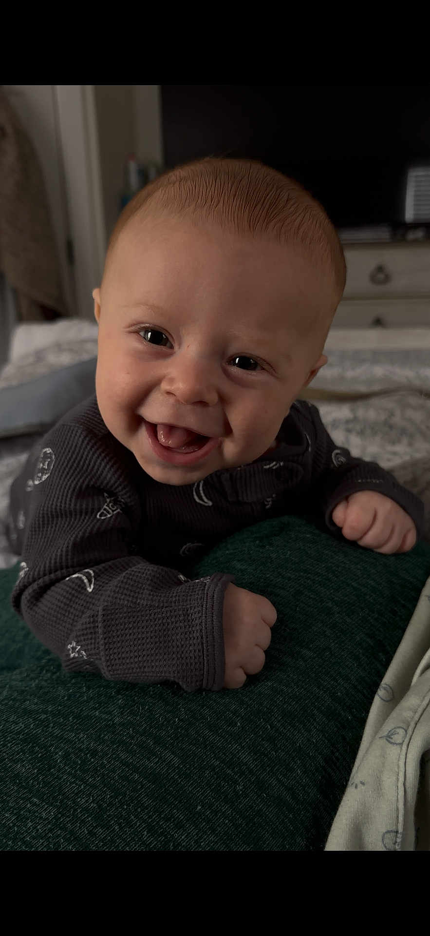 Maverick is registered to the contest to win money with this photo: baby, smiling, face, infant, hands, clothing, cushion, indoor, bedroom, person, cute, happy, portrait, closeup, child, toddler, skin, head, expression, young