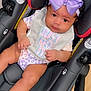 True is registered to the contest to win money with this photo: baby, car_seat, purple_bow, bib, clothing, infant, child, face, person, cute, sitting, indoor, footwear, nike, black_hair, skin, expression, looking, headband, legs