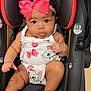 baby, car_seat, pink_bow, infant, cute, child, clothing, white_outfit, heart_pattern, cat_pattern, chubby_cheeks, curious_expression, sitting, seatbelt, headband, indoors, black_hair, skin, portrait, closeup