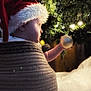 baby, child, santa_hat, christmas_tree, ornament, holiday, festive, lights, knitted_basket, cozy, indoor, decorations, curious, soft_lighting, seasonal, winter, cute, celebration, infant, warmth