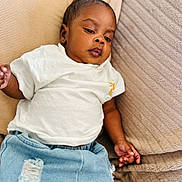 Muhammad a rejoint le concours — aidez-le/la à gagner de superbes lots ! baby, child, infant, clothing, white_tshirt, blue_jeans, couch, cushion, indoor, relaxed, portrait, person, young_child, casual, cute, skin, face, hand, seated, comfort