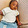 baby, child, infant, clothing, white_tshirt, blue_jeans, couch, cushion, indoor, relaxed, portrait, person, young_child, casual, cute, skin, face, hand, seated, comfort