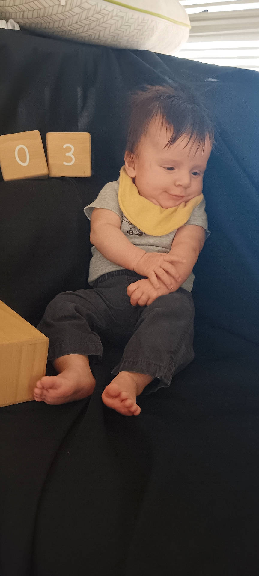 Jaxon is registered to the contest to win money with this photo: baby, bodypart, box, cardboard, carton, clothing, couch, face, finger, furniture, hand, head, newborn, pants, person, photography, portrait, sitting, t_shirt, wood