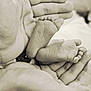 baby_feet, adult_hands, black_and_white, close_up, tender, newborn, foot, hand, skin, protection, care, small, soft, blurred_background, family, love, parent, infant, touch, comfort