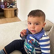 Louis participe au concours pour gagner de l'argent avec cette photo : blue, casual_clothing, child, couch, curious, face, furniture, home, indoor, person, pillow, portrait, seated, socks, striped_shirt, table, toddler, toy, white, young_child
