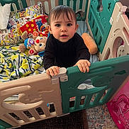 Mia joined the competition — help win amazing prizes! toddler, child, playpen, toy, blanket, plush_toy, indoor, curious, standing, pigtails, baby, furniture, carpet, colorful, gate, hands, clothing, face, person, home