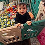 toddler, child, playpen, toy, blanket, plush_toy, indoor, curious, standing, pigtails, baby, furniture, carpet, colorful, gate, hands, clothing, face, person, home