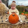 baby, child, pumpkin, hay, autumn, outdoor, knit_hat, sweater, blanket, grass, fall, cute, surprised_expression, nature, seasonal, person, smile, funny_face, pom_pom, festival