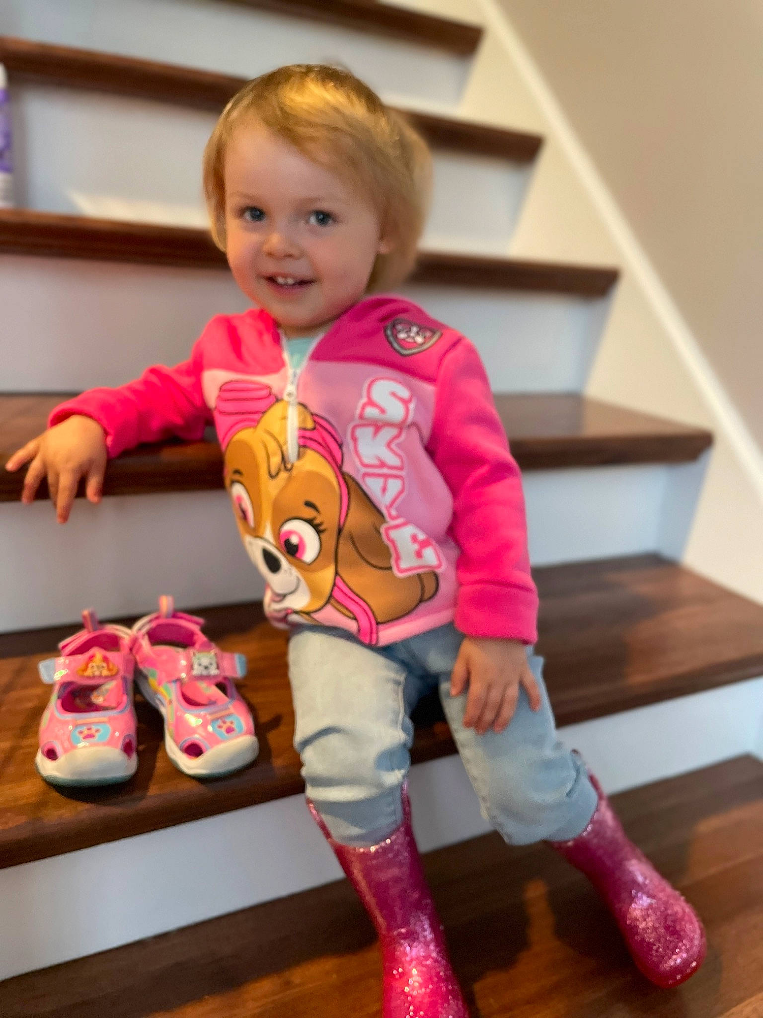 Maya is registered to the contest to win money with this photo: baby, baby_toddler_clothing, child, flooring, fun, happy, hardwood, human_leg, joy, knee, magenta, person, pink, shoe, skin, sleeve, smile, sock, standing, thigh