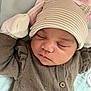 baby, sleeping, hat, striped_hat, bear_ears, knitted_sweater, brown_sweater, infant, cute, cozy, soft_surface, blanket, pink_blanket, newborn, face, closed_eyes, resting, child, cute_outfit, adorable