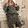 baby, blanket, child, cute, grey_outfit, indoor, infant, lying_down, newborn, pacifier, patterned_bedding, plush_toy, polka_dots, portrait, resting, sleepwear, sloth, soft_texture, white_hat, white_socks