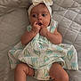 Yasliet is registered to the contest to win money with this photo: baby, infant, child, girl, dress, headband, bow, flower_pattern, hand, legs, socks, quilted_bedspread, curious_expression, lying_down, skin, cute, indoors, portrait, soft_lighting, candid