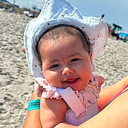 Emilia joined the competition — help win amazing prizes! baby, child, smiling, hat, sunhat, beach, sand, sunny, outdoor, person, face, arm, clothing, cute, happy, daylight, infant, holding, summer, vacation