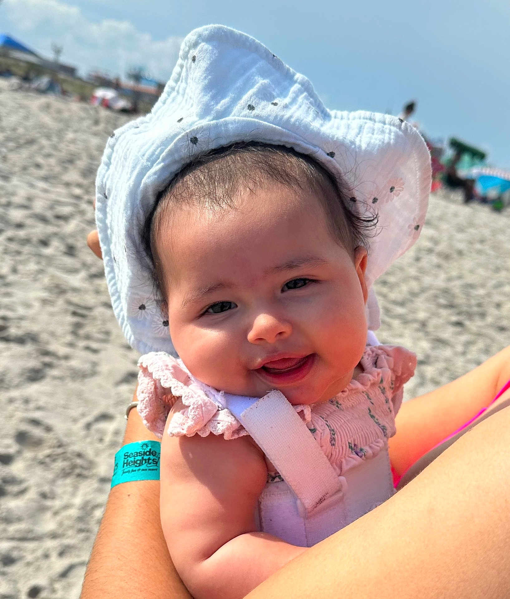 Emilia joined the competition — help win amazing prizes! baby, child, smiling, hat, sunhat, beach, sand, sunny, outdoor, person, face, arm, clothing, cute, happy, daylight, infant, holding, summer, vacation