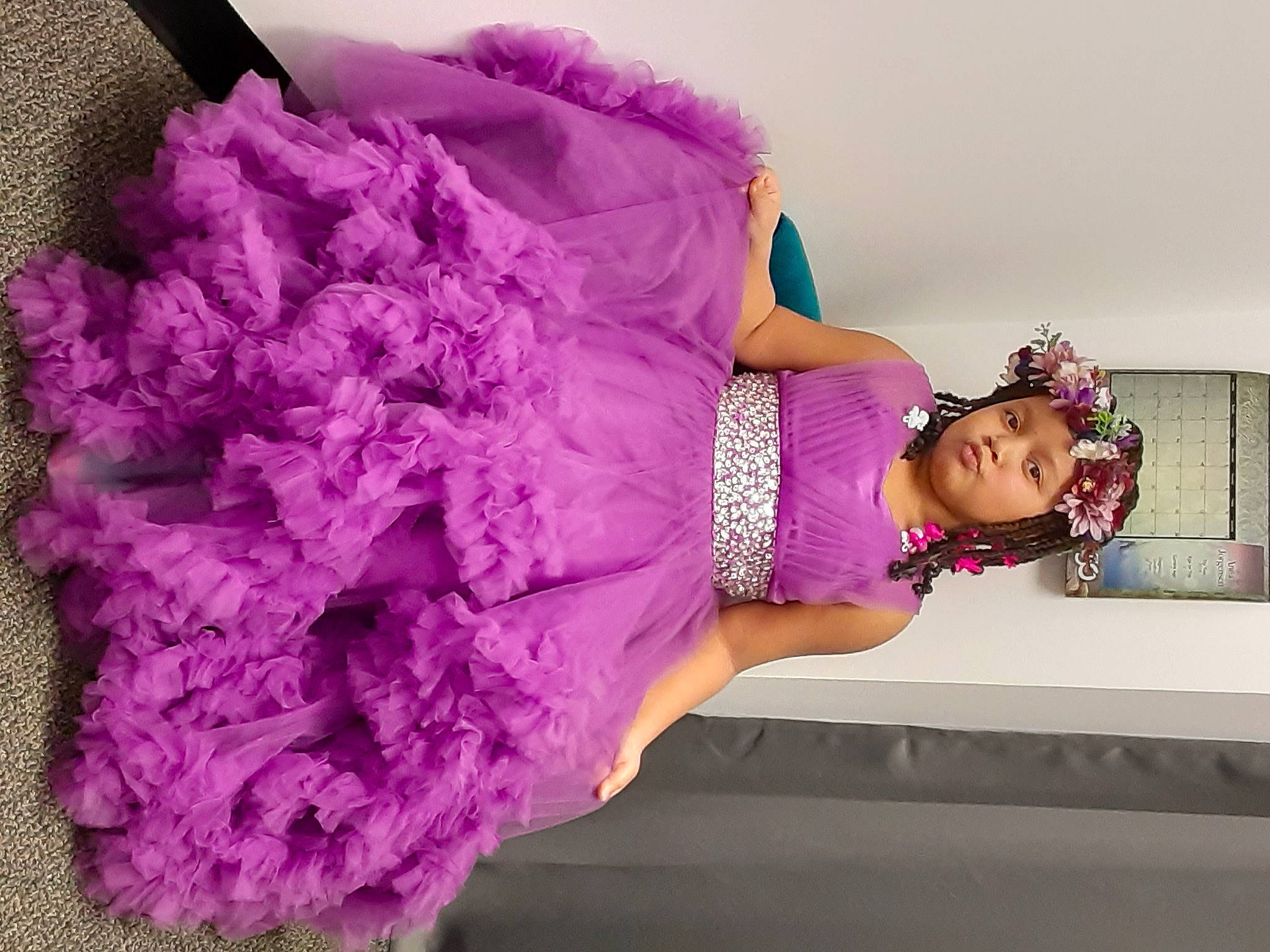 Layla is registered to the contest to win money with this photo: arm, day_dress, dress, face, fashion_design, happy, headgear, headwear, human_body, leg, magenta, one_piece_garment, person, petal, pink, plant, purple, shoulder, textile, thigh