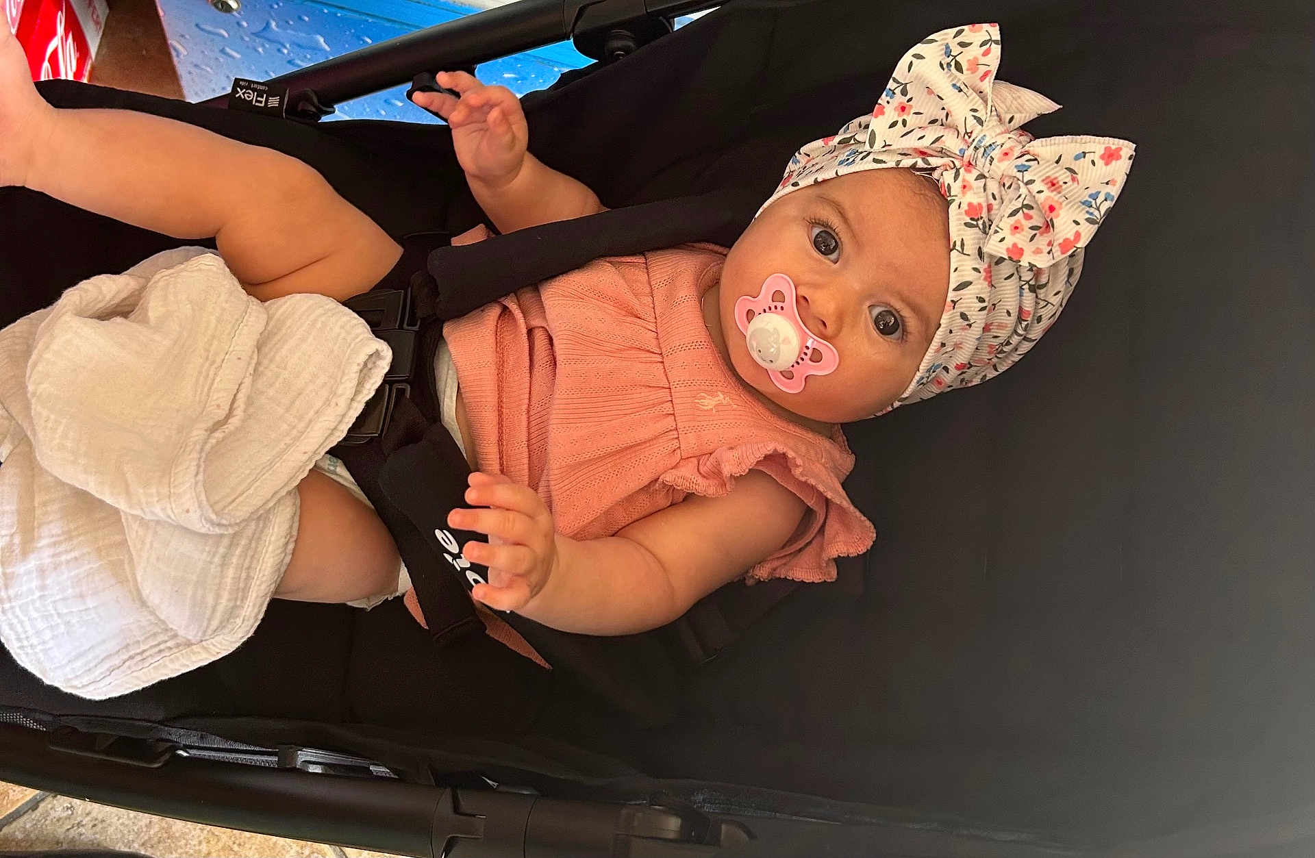 Arya participe au concours pour gagner de l'argent avec cette photo : baby, child, stroller, pacifier, headwrap, floral, pink_clothing, blanket, infant, cute, curious, hand, foot, seatbelt, soft_fabric, portrait, indoors, person, closeup, baby_girl