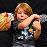 Dakota is registered to the contest to win money with this photo: child, boy, red_hair, thumbs_up, knitted_toy, plush_toy, beanbag, black_background, casual_clothing, surprised_expression, indoor, portrait, cute, smiling, short_sleeves, playful, seated, young, happy, cozy