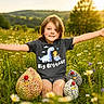 arms_outstretched, big_brother, boy, child, cute, flowers, grass, greenery, happy, knitted_chicken, meadow, nature, outdoor, playful, portrait, smiling, summer, sunlight, sunset, tshirt