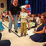 Dakota joined the competition — help win amazing prizes! child, graduation, diploma, balloons, celebration, kindergarten, paper_hat, group, people, indoor, floor, stage, adult, smile, clothing, microphone, event, happy, school, seated
