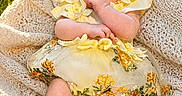 Eloise joined the competition — help win amazing prizes! baby, infant, yellow_dress, headband, flower, blanket, outdoor, grass, sunlight, nature, cute, smiling, portrait, child, happy, summer, flower_field, skin, feet, hand