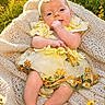 Eloise joined the competition — help win amazing prizes! baby, infant, yellow_dress, headband, flower, blanket, outdoor, grass, sunlight, nature, cute, smiling, portrait, child, happy, summer, flower_field, skin, feet, hand