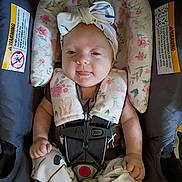 Eloise joined the competition — help win amazing prizes! baby, infant, car_seat, headband, flower_pattern, pacifier, smile, tongue_out, sitting, straps, clothing, cute, child, indoors, fabric, safety_harness, person, playful, young, seat