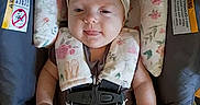 Eloise joined the competition — help win amazing prizes! baby, car_seat, child, clothing, cute, fabric, flower_pattern, headband, indoors, infant, pacifier, person, playful, safety_harness, seat, sitting, smile, straps, tongue_out, young