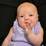 Eloise is registered to the contest to win money with this photo: baby, infant, child, purple_dress, lace, bow, hand, face, skin, person, cute, smiling, sitting, portrait, indoors, young_child, expression, happy, close_up, background