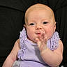 baby, infant, child, purple_dress, lace, bow, hand, face, skin, person, cute, smiling, sitting, portrait, indoors, young_child, expression, happy, close_up, background